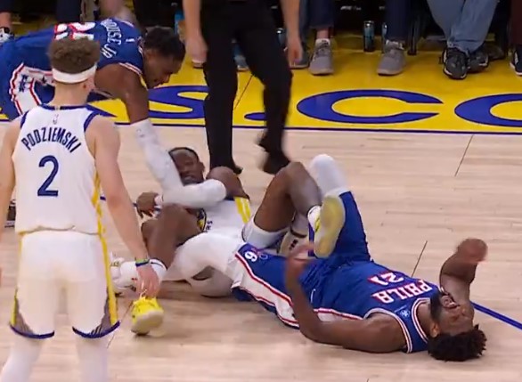 Joel Embiid writhes in pain after reinjuring his left knee late in the fourth quarter of the 76ers' 119-107 loss to the Warriors.