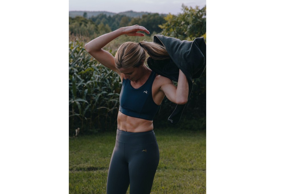 a woman in sports garment holding a jacket over her shoulder