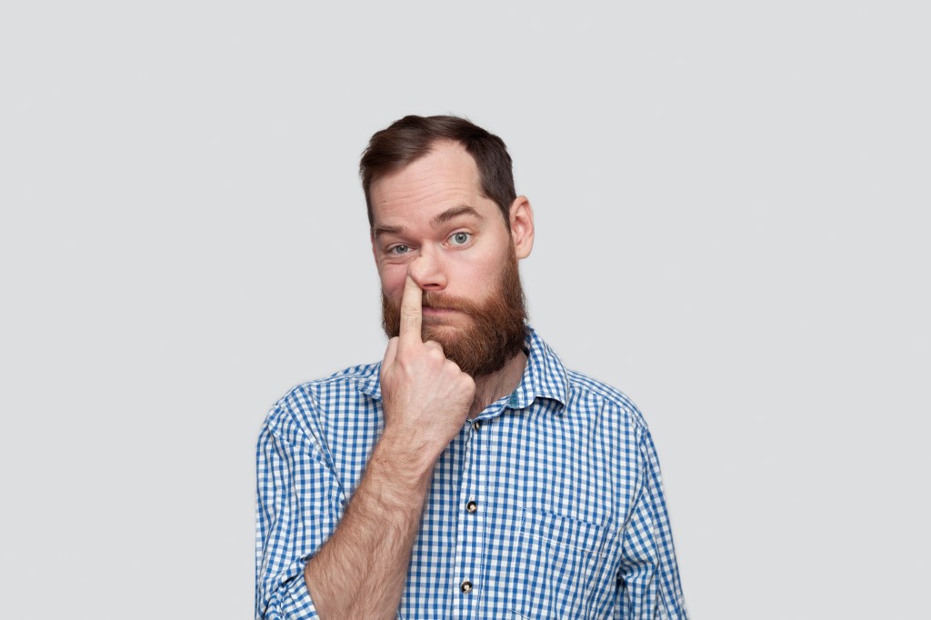 Portrait of a man sticking his finger in the nose 