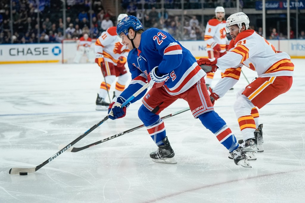 Adam Fox moves the puck up the ice against the Flames.