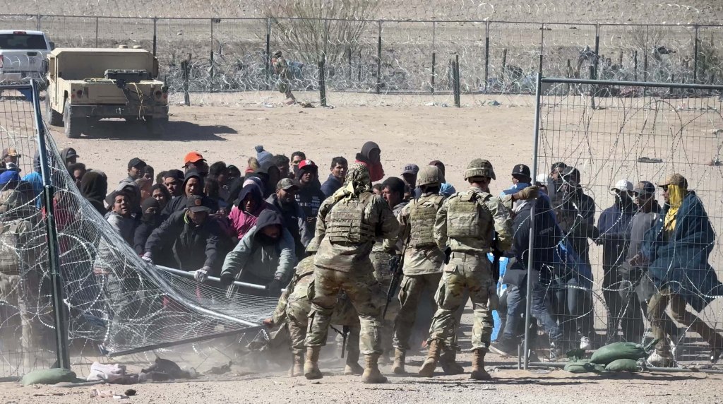 These are the chaotic scenes as a group of over 100 migrants attempt to enter the US illegally by rushing a border wall on Thursday, breaking through razor wire and knocking over guards in the process.,