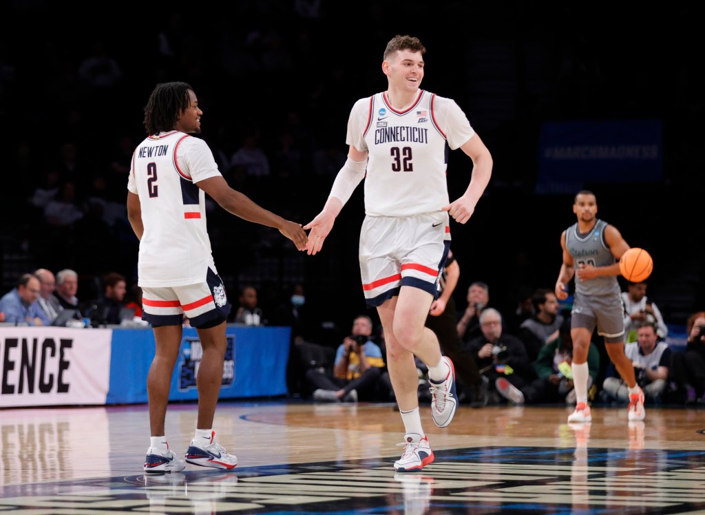 Connecticut Huskies center Donovan Clingan (C) celebrates his dunk past a defending Stetson Hatters guard Stephan Swenson (L) and teammate Stetson Hatters forward Treyton Thompson (R) in the second half during the NCAA Tournament First Round game at the Barclays Center in Brooklyn