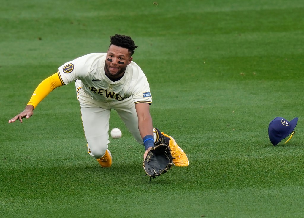 Brewers center fielder Jackson Chourio dives for a hit by Cincinnati Reds Tyler Callihan during the third inning of a spring training baseball game.