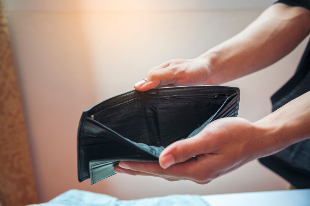 A person showing an open, empty wallet signifying unemployment and poverty