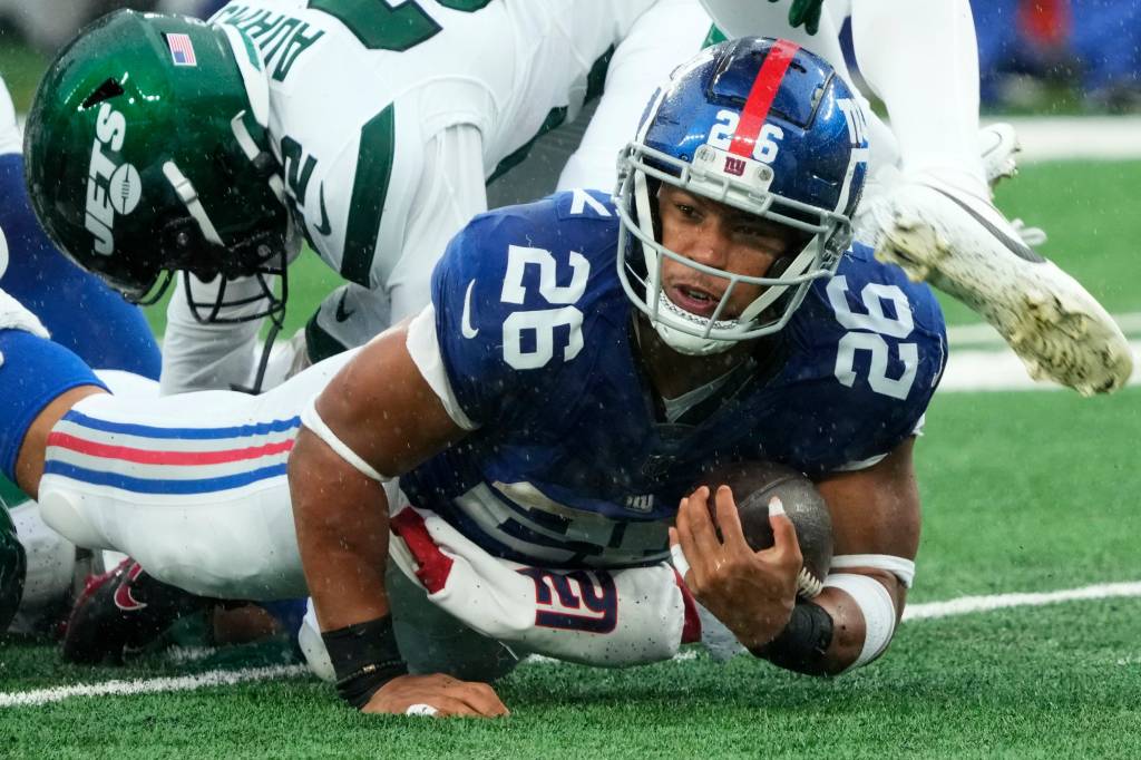 Giants running back Saquon Barkley (26) holds onto the ball as he is tackled against the Jets.