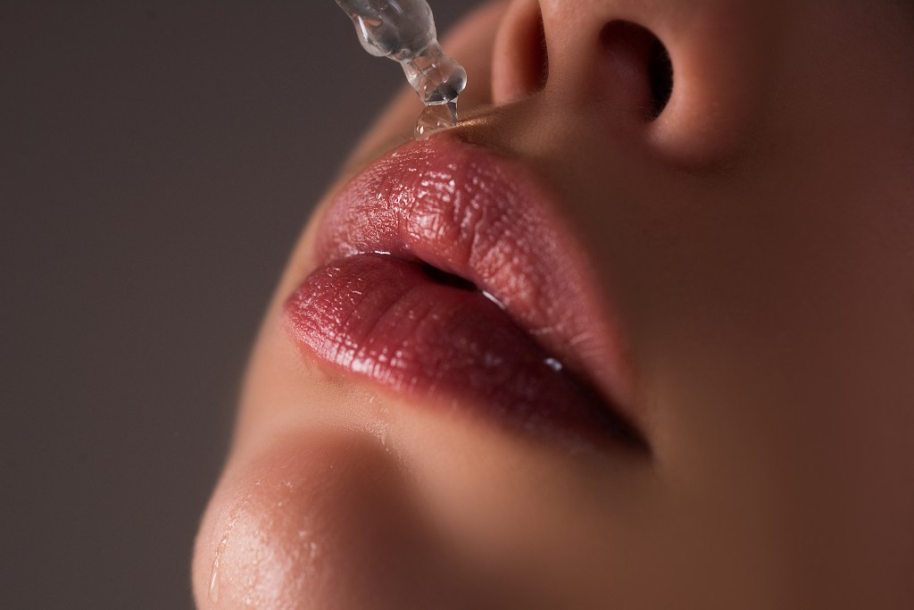 Close-up of a woman's lips being treated with hyaluronic acid and lip oil for lip care