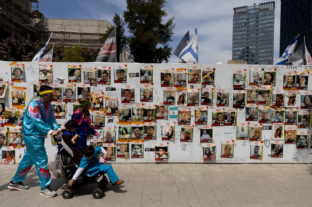 Israelis walk past a wall depicting the hostages in Gaza during the Purim holiday on Sunday.