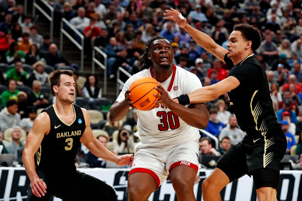 DJ Burns, who scored 24 points and grabbed 11 rebounds, goes up for a shot as Jack Gohlke (left) and Chris Conway defend during North Carolina  State's 79-73 OT win over Oakland in the second round of the NCAA Tournament.