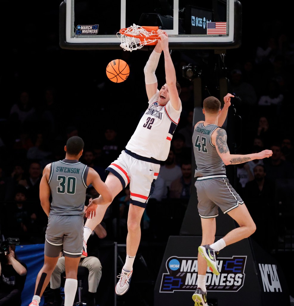 Connecticut Huskies center Donovan Clingan (C) dunks past a defending Stetson Hatters guard Stephan Swenson (L) and teammate Stetson Hatters forward Treyton Thompson (R) in the second half during the NCAA Tournament First Round game at the Barclays Center in Brooklyn, New York