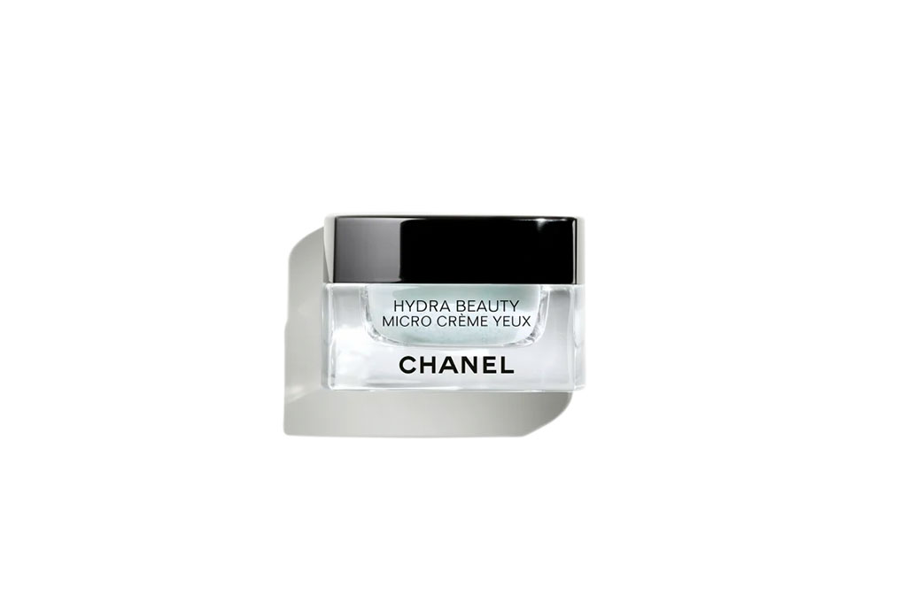 A clear container with a black lid labeled as eye cream