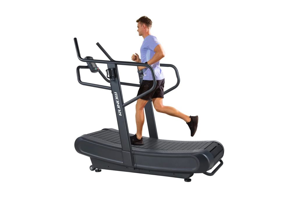 Man on self powered treadmill with long handrails. 