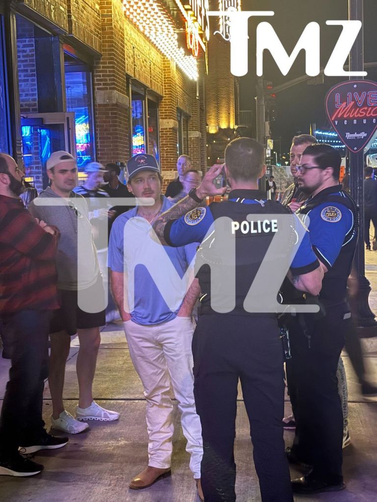 Morgan Wallen standing on a sidewalk with police officers