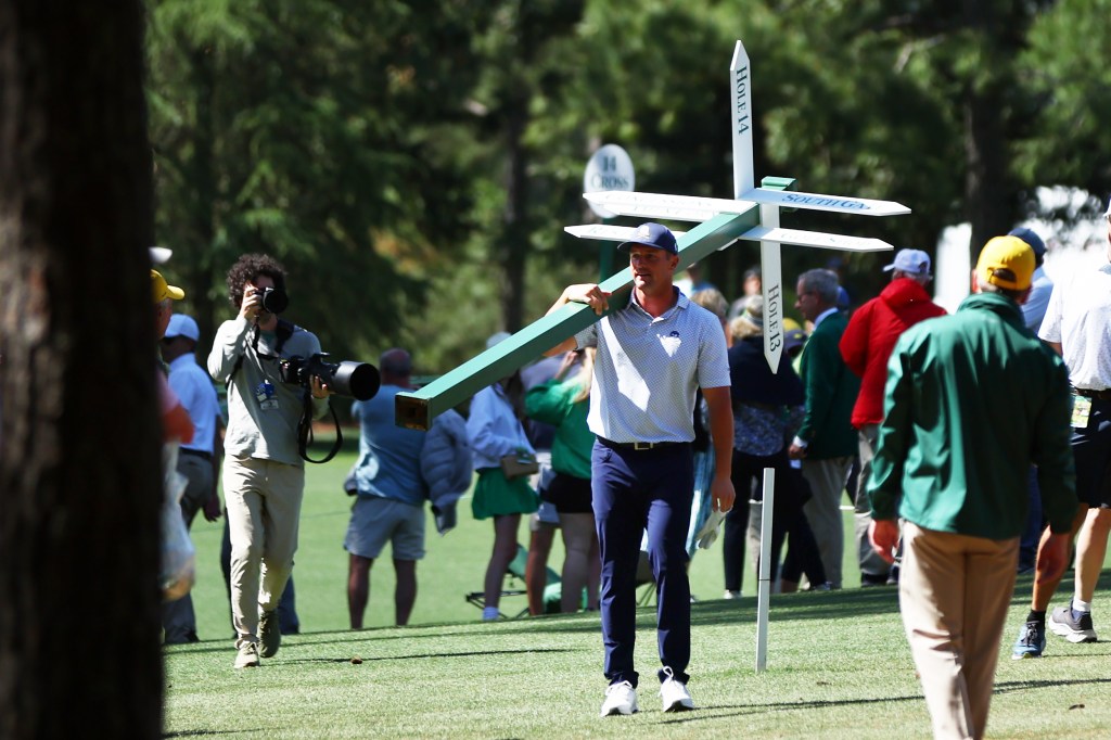 Bryson DeChambeau moves a sign while preparing to play his second shot on the 13th hole during the second round of the 2024 Masters Tournament.