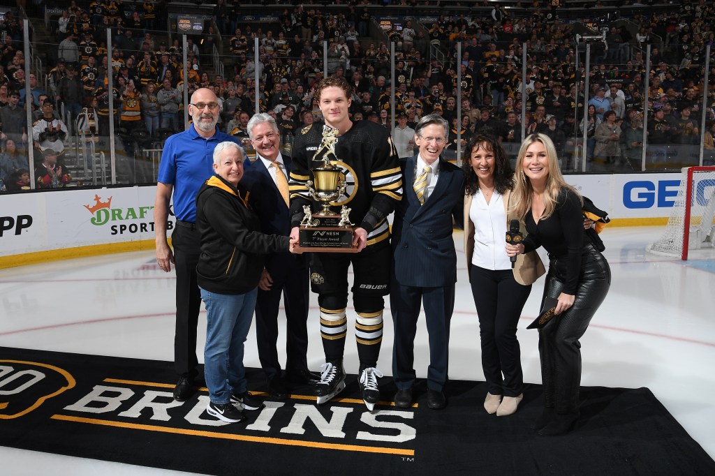 Two fans, NESN CEO Sean McGrail, NESN Broadcasters Jack Edwards, Rose Mirakian-Wheeler and Sophia Jurjsztowicz present the 7th Player Award to Trent Frederic #11 of the Boston Bruins before the game against the Ottawa Senators at the TD Garden on April 16, 2024 in Boston, Massachusetts. 