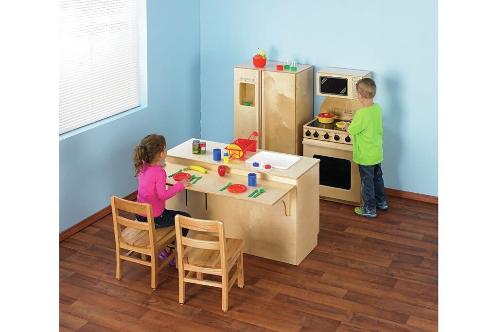 A boy and girl playing in a play kitchen