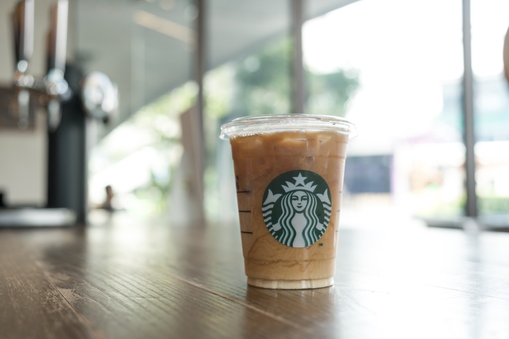 Glass of Starbucks iced coffee on a table in a Starbucks coffee shop in Samut Prakan, Thailand.