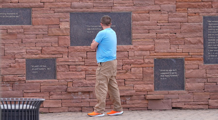 A visitor looks at the plaques on the wall of healing at the Columbine Memorial