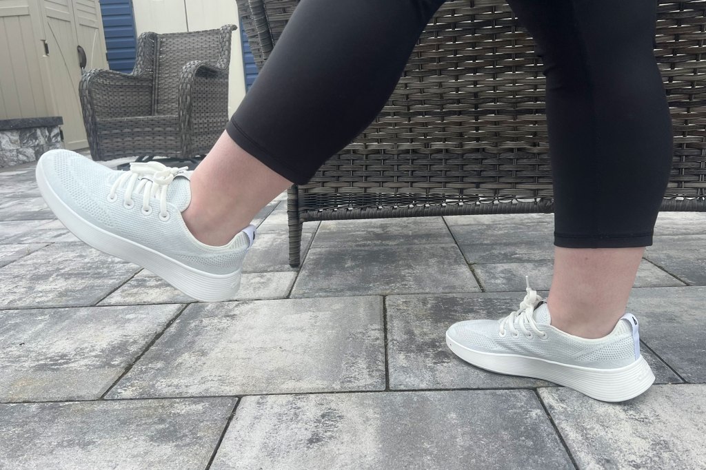 A person's legs and feet wearing white Allbirds shoes in motion