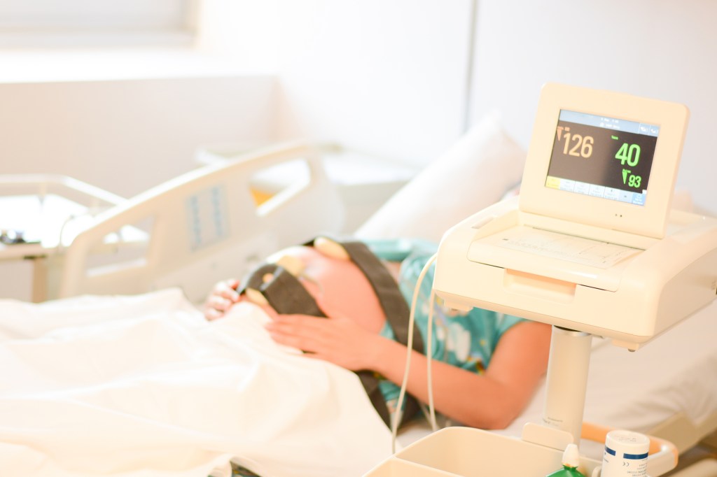 Pregnant woman in a hospital bed undergoing cardio monitoring before giving birth