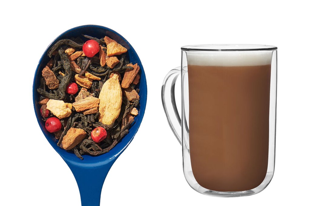 A spoon with a mixture of herbs and spices next to a mug of coffee