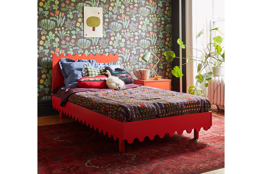 A bed with a red bed frame and a red rug 