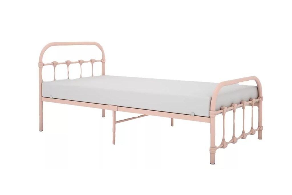 A pink metal bed with a white sheet