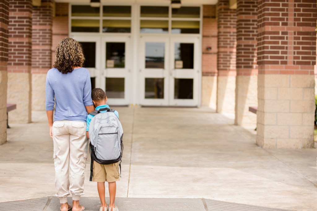 Boy and mom stand in front of school