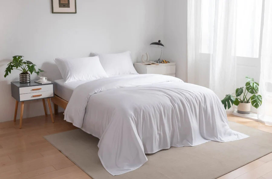 A bed with white bamboo sheets and pillows