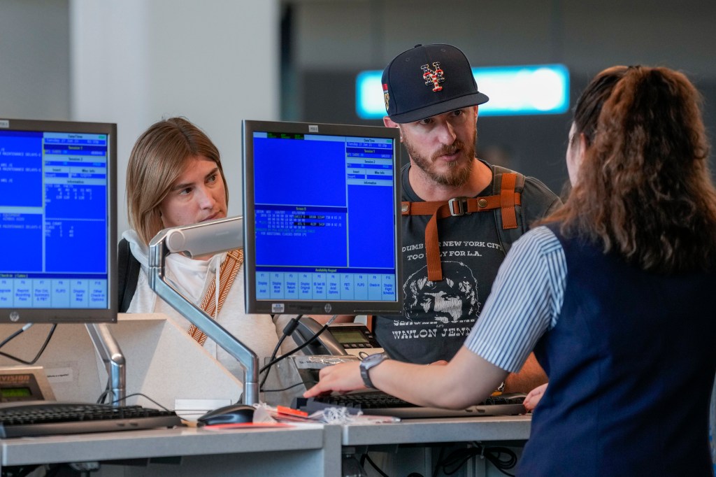 A airline agents helps a travelers in the departures area of Terminal B at LaGuardia Airport, Tuesday, June 27, 2023