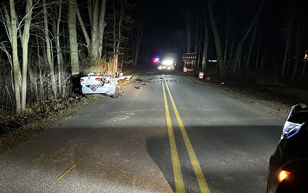 Image of totaled white car on the side of the road.