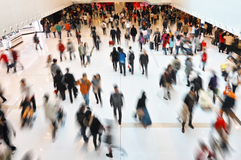 A crowd of people walking in a shopping mall. 