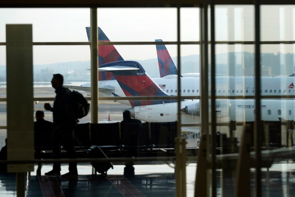 A person walks through the terminal as planes remain at gates at Ronald Reagan Washington National Airport in Arlington, Va., Wednesday, Jan. 11, 2023.