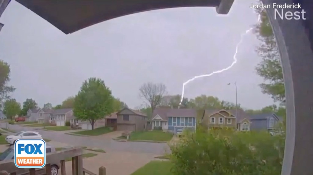 Lightning bolt striking near a house under dark and stormy Kansas City skies