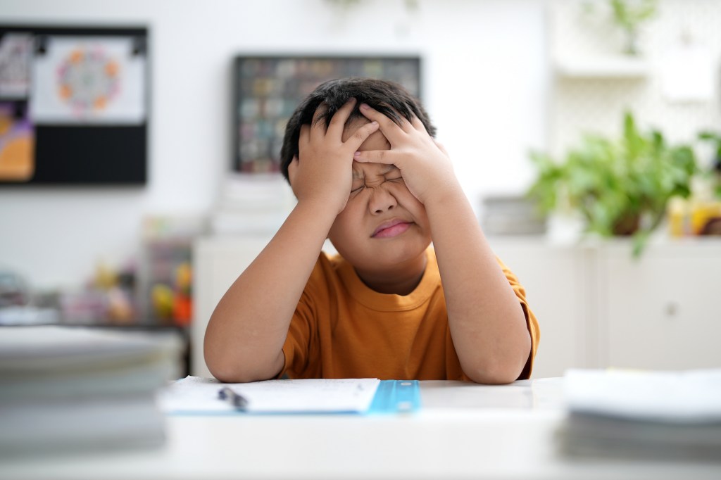 Young boy is tired of doing homework, sitting at the table.