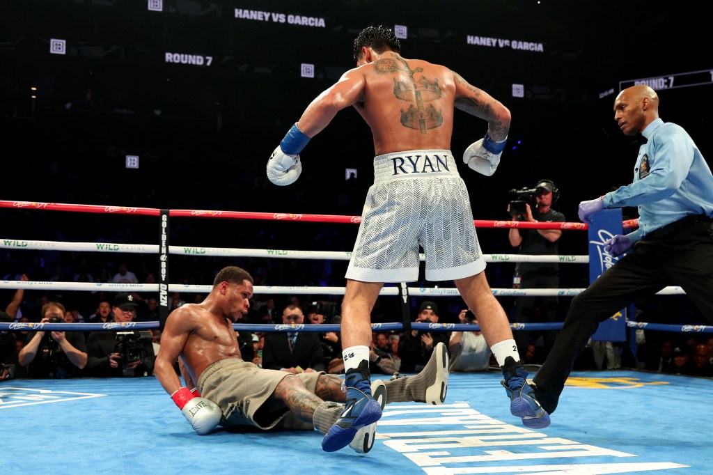 Ryan Garcia (white trunks) knocks down Devin Haney (gray trunks) during their WBC Super Lightweight title bout at Barclays Center on April 20, 2024 in New York City.