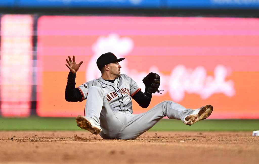 Giants shortstop Nick Ahmed falls to the ground after getting his cleat caught in the dirt while attempting a throw.