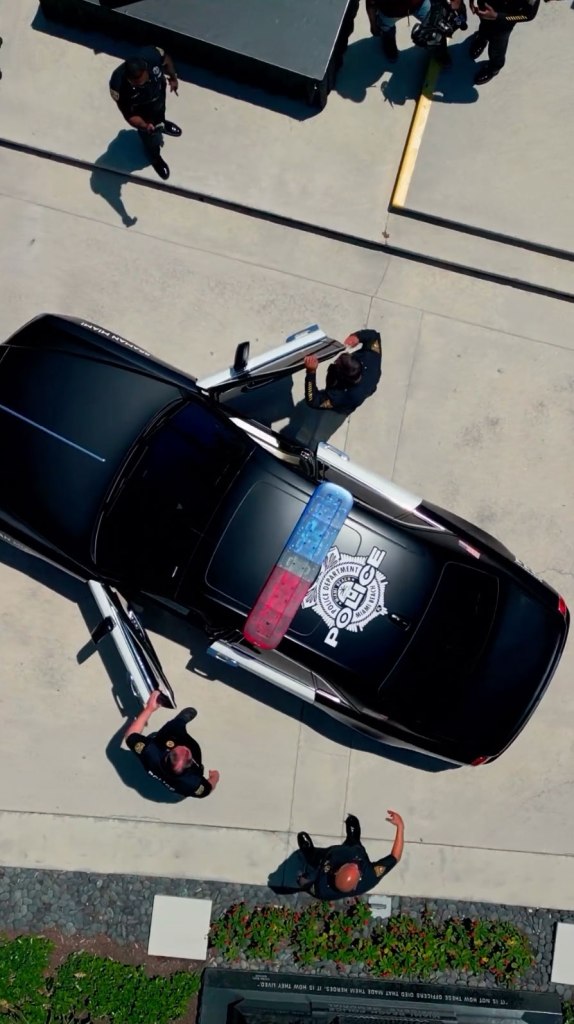 Police officers maintaining a car sponsored by Braman Motors for the MBPD recruitment team