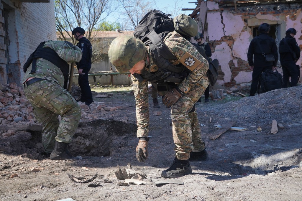 A police officer wearing a camouflage uniform examines fragments of a guided bomb after the Russian air raid in Kharkiv, Ukraine, on April 30.