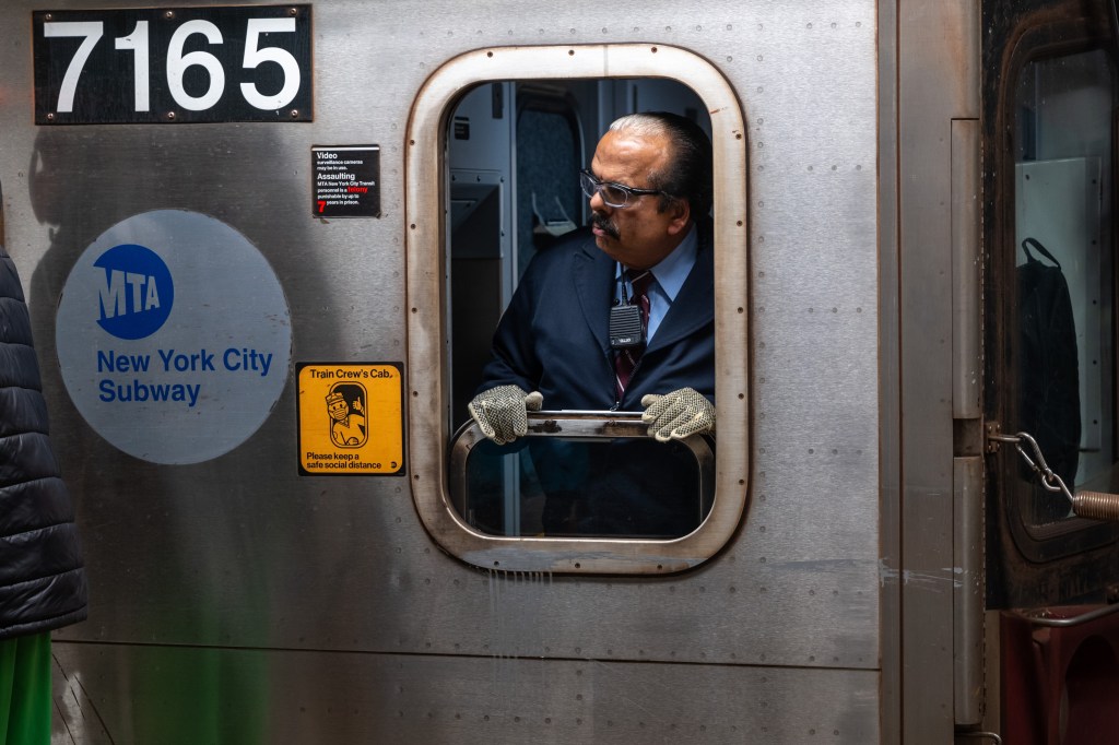 A conductor on a train monitors the platform at a subway station.