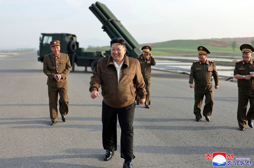 North Korean leader Kim Jong Un walks from a rocket launch site with four people behind him.