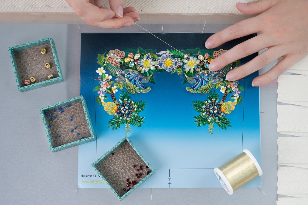 A person sewing a picture with a needle in a Mary Katrantzou and Bulgari collaboration