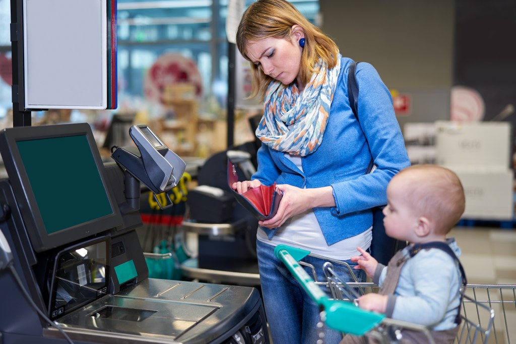 Stock photo of woman with baby at self checkout.