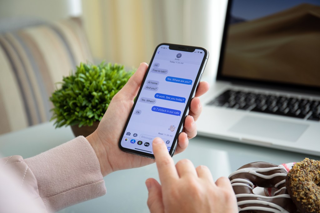 Woman hand holding iPhone X with social networking service iMessage on the screen.