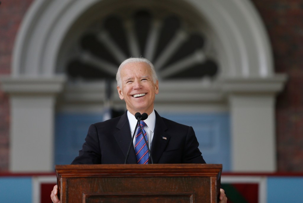 Former Vice President Joe Biden laughing while speaking at a podium during Harvard University's Class Day Exercises