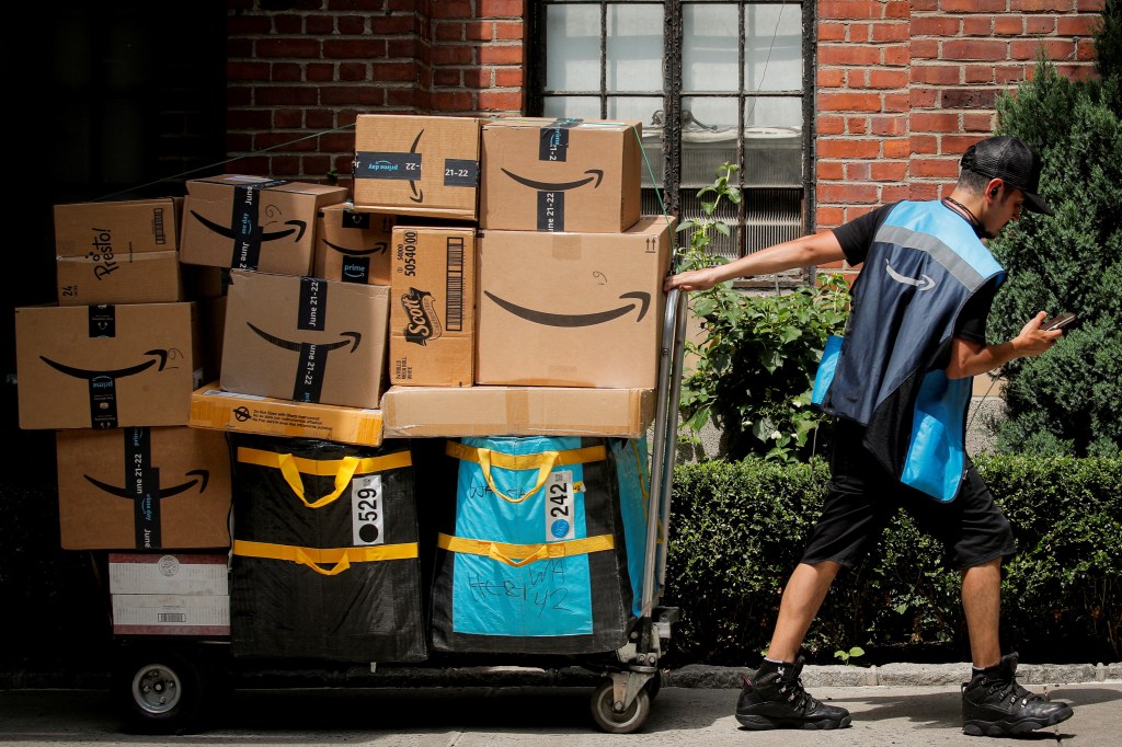 Amazon delivery worker pulling a cart filled with packages during Prime Day promotion in New York City