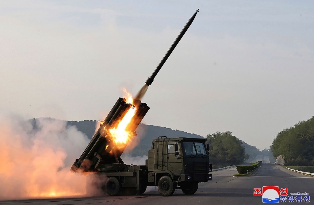 A multiple rocket launch system on fire as it's angled up toward the sky.