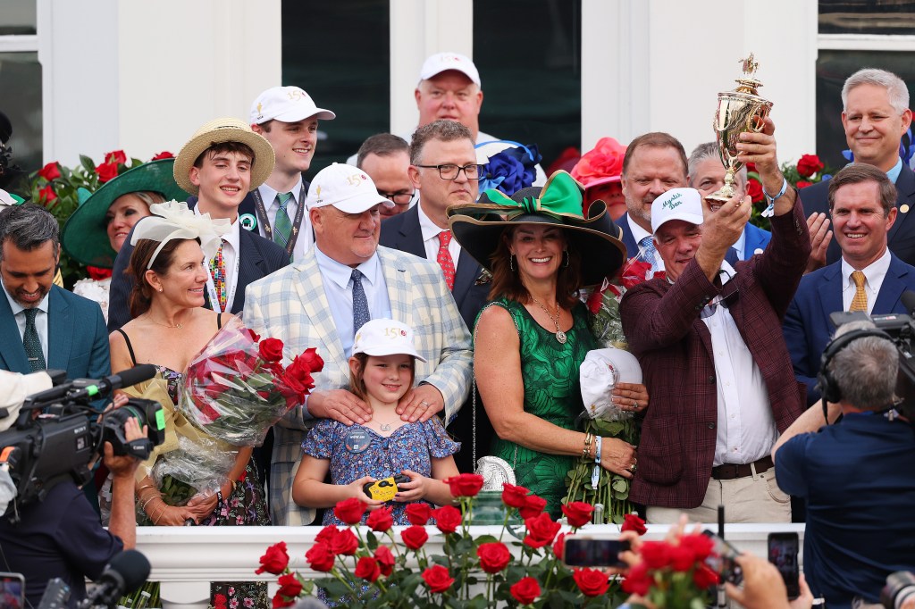 Mystik Dan owner Lance Gasaway raises the trophy after winning the 150th running of the Kentucky Derby.