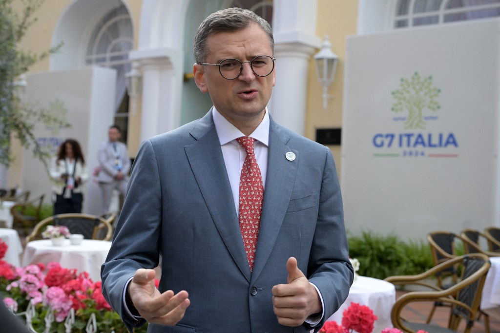 Dmytro Kuleba, the Ukrainian foreign minister, wearing a grey suit with a red tie, gestures with his hands as he speaks.