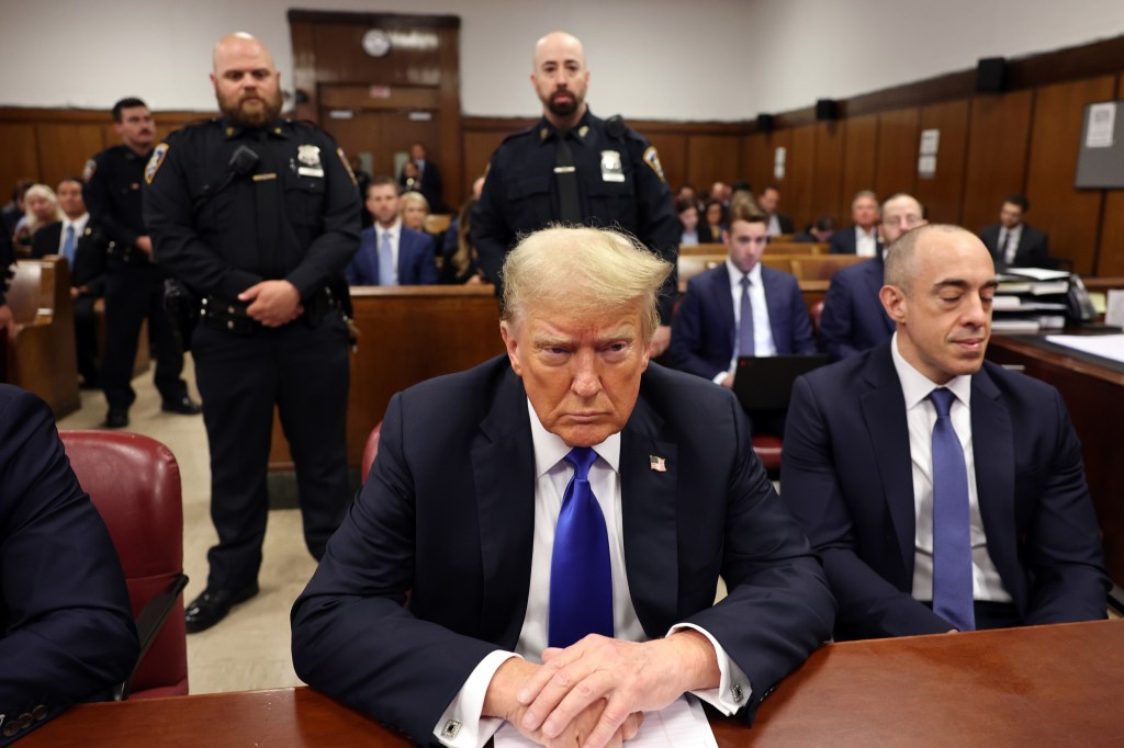 Trump  seen in court seated on May 30, 2024 with court officers standing behind him