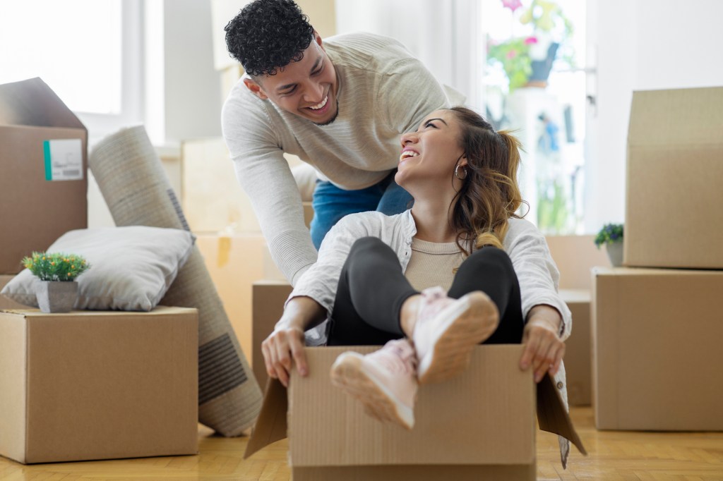 Young couple laughing and sitting in a moving box